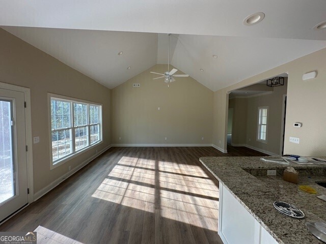 living room featuring dark hardwood / wood-style flooring, plenty of natural light, ceiling fan, and vaulted ceiling