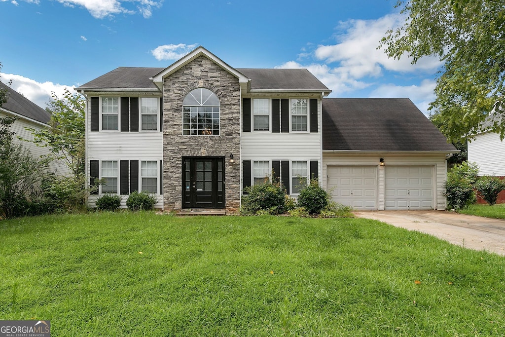 1125 Misty Meadows Ln, Hampton, GA 30228 - colonial-style house featuring stone siding, an attached garage, driveway, and a front lawn