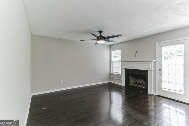 unfurnished living room with ceiling fan, plenty of natural light, dark hardwood / wood-style floors, and a textured ceiling