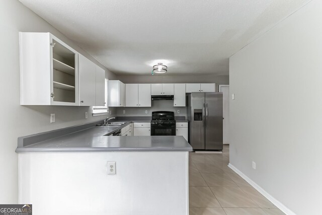 kitchen featuring light tile patterned floors, black range with gas cooktop, kitchen peninsula, sink, and stainless steel refrigerator with ice dispenser