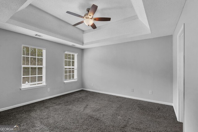 carpeted spare room featuring a textured ceiling, a raised ceiling, and ceiling fan