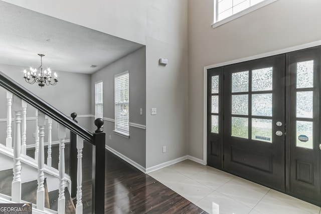 entryway with vaulted ceiling, a textured ceiling, a notable chandelier, and light hardwood / wood-style floors