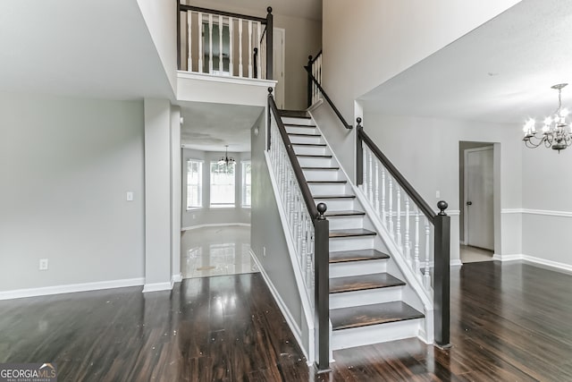 stairs with wood-type flooring and a chandelier