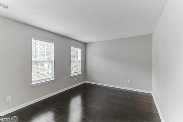 empty room featuring a textured ceiling and dark hardwood / wood-style floors