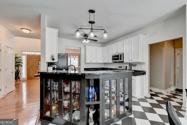 kitchen with ceiling fan with notable chandelier, stainless steel appliances, dark hardwood / wood-style flooring, sink, and hanging light fixtures