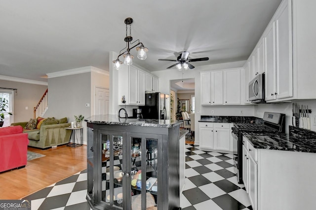 kitchen featuring white cabinetry, black fridge, gas range oven, ceiling fan, and pendant lighting