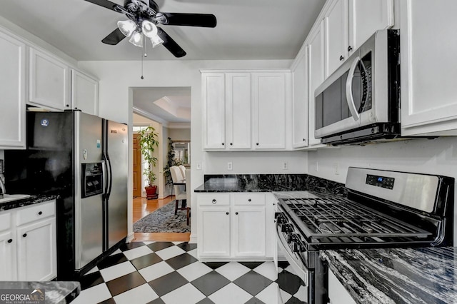 kitchen featuring dark stone countertops, white cabinetry, stainless steel appliances, and ceiling fan