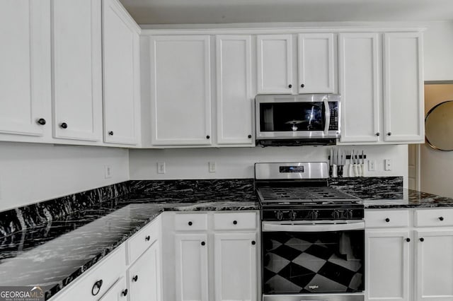 kitchen with stainless steel appliances, dark stone counters, and white cabinetry