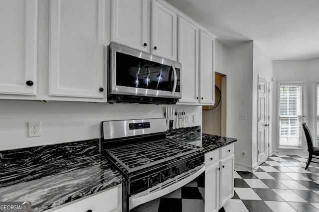 kitchen with dark stone countertops, appliances with stainless steel finishes, and white cabinetry