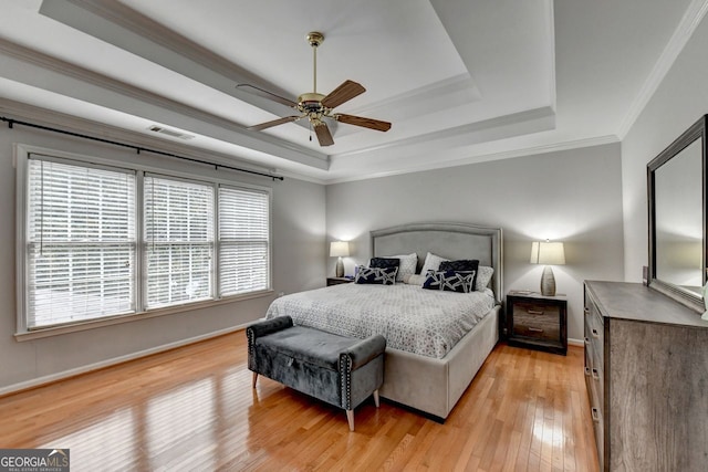 bedroom with a raised ceiling, ceiling fan, ornamental molding, and hardwood / wood-style floors