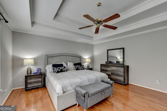 bedroom with crown molding, a raised ceiling, light hardwood / wood-style flooring, and ceiling fan