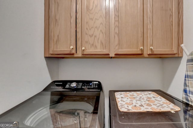 clothes washing area with washer / clothes dryer and cabinets