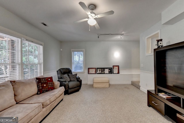 living room featuring rail lighting, ceiling fan, and light carpet