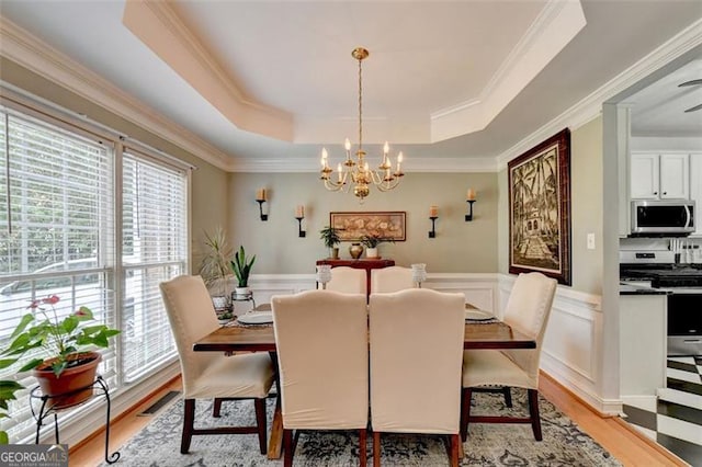 dining room featuring a tray ceiling, light wood-type flooring, and a wealth of natural light