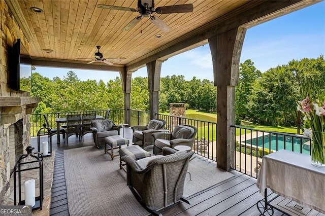 wooden deck with outdoor lounge area, ceiling fan, and a fenced in pool