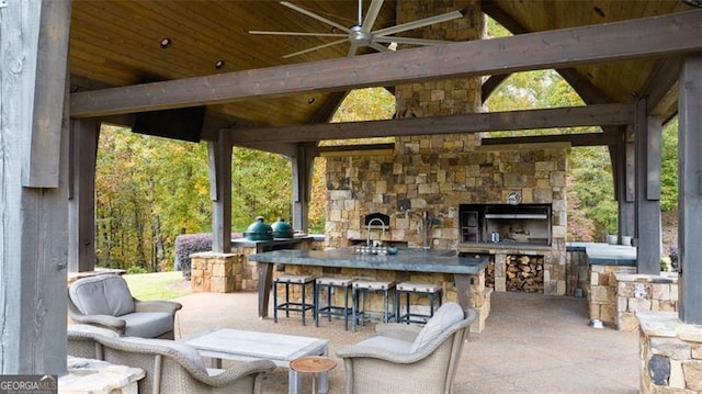 view of patio / terrace with an outdoor bar, an outdoor stone fireplace, and ceiling fan