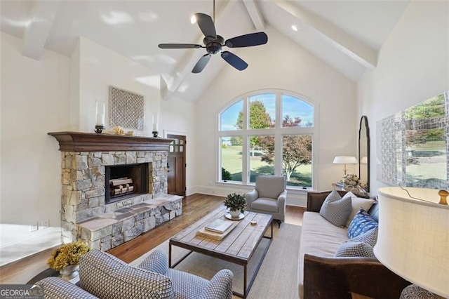 living room with a fireplace, high vaulted ceiling, hardwood / wood-style floors, ceiling fan, and beam ceiling