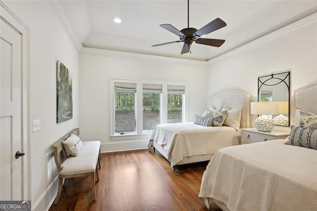 bedroom featuring dark wood-type flooring, a tray ceiling, ceiling fan, and ornamental molding