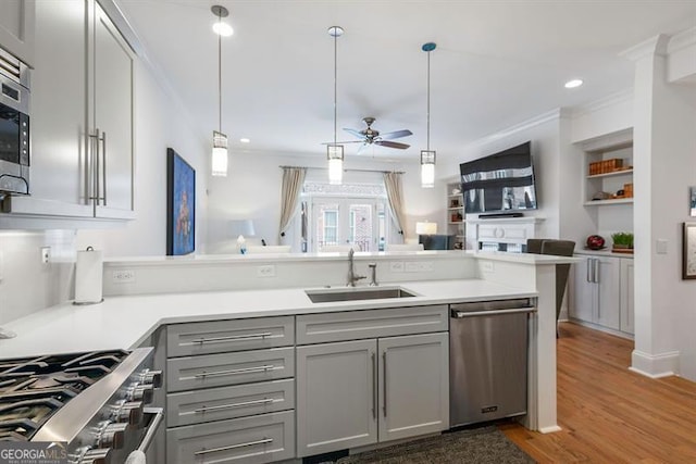 kitchen featuring hardwood / wood-style flooring, appliances with stainless steel finishes, sink, kitchen peninsula, and ceiling fan