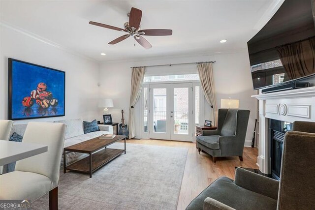 living room featuring crown molding, ceiling fan, french doors, and light hardwood / wood-style floors