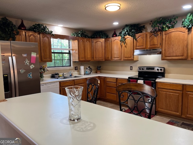 kitchen featuring a textured ceiling, sink, light tile patterned floors, and appliances with stainless steel finishes