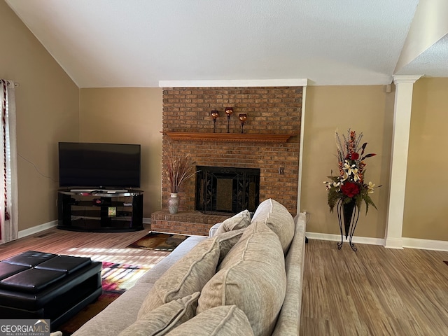 living room featuring hardwood / wood-style flooring, a brick fireplace, and vaulted ceiling