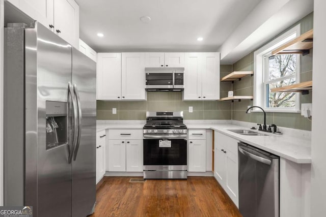 kitchen featuring dark hardwood / wood-style flooring, appliances with stainless steel finishes, sink, decorative backsplash, and white cabinets