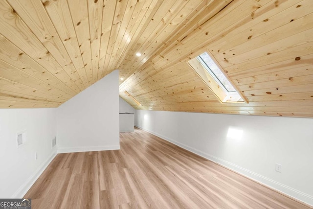 additional living space featuring vaulted ceiling with skylight, wooden ceiling, and light hardwood / wood-style floors