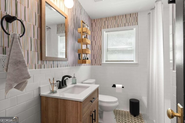 full bathroom with vanity, toilet, plus walk in shower, and tile walls