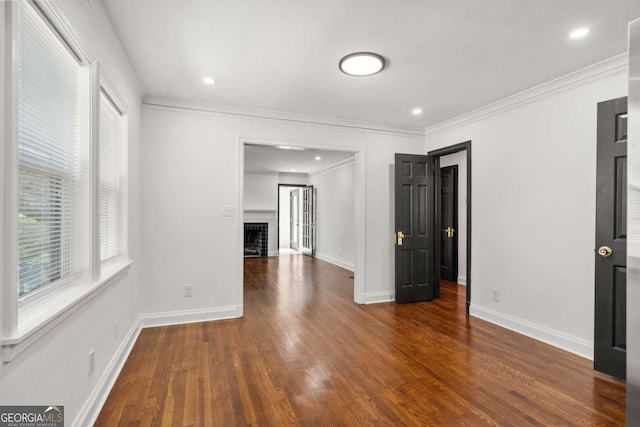 unfurnished living room featuring ornamental molding and dark hardwood / wood-style flooring