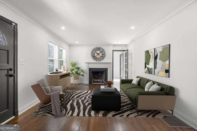 living room with hardwood / wood-style floors, a tiled fireplace, and crown molding