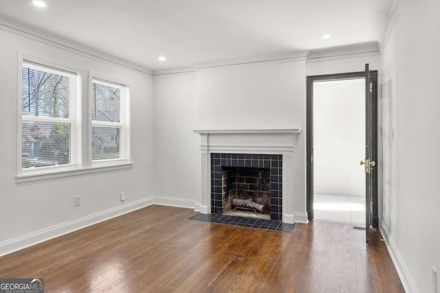 unfurnished living room featuring ornamental molding, dark wood-type flooring, and a tile fireplace