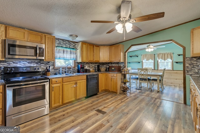 kitchen with light wood-type flooring, stainless steel appliances, ceiling fan, ornamental molding, and a textured ceiling