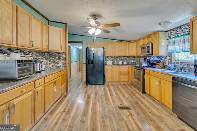 kitchen featuring light wood-type flooring, tasteful backsplash, sink, ceiling fan, and appliances with stainless steel finishes