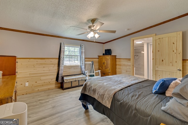 bedroom featuring a textured ceiling, ceiling fan, ornamental molding, and wooden walls