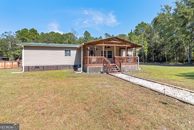 view of front of house with a wooden deck, ceiling fan, and a front yard