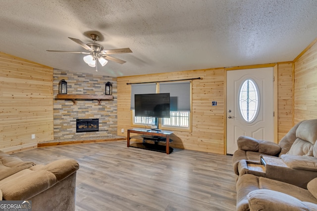 living room with a fireplace, a textured ceiling, wood-type flooring, and ceiling fan