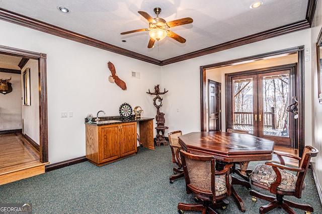 carpeted dining room with a textured ceiling, french doors, sink, ceiling fan, and ornamental molding