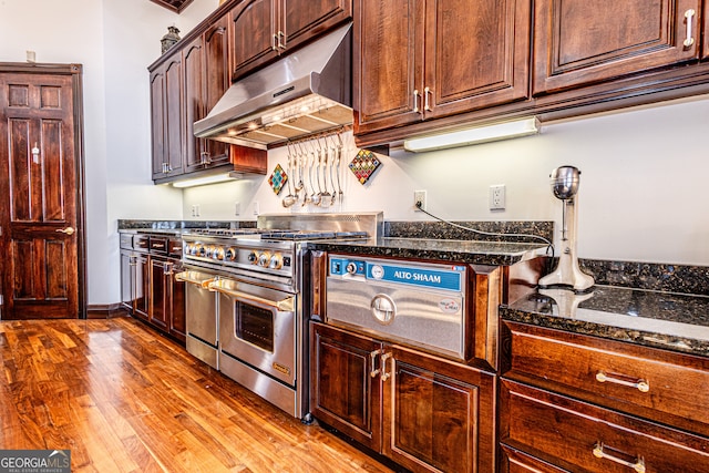 kitchen featuring dark stone counters, double oven range, and light hardwood / wood-style flooring