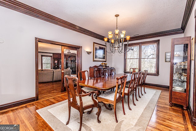 dining room featuring ornamental molding, a notable chandelier, light wood-type flooring, and a textured ceiling