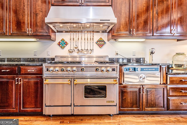 kitchen featuring stainless steel range, dark stone counters, and light hardwood / wood-style flooring