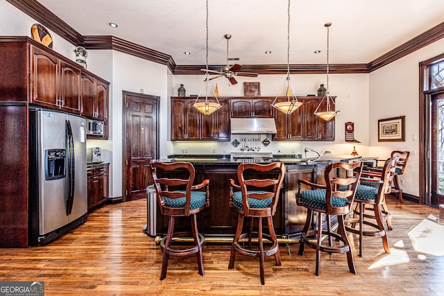 kitchen with decorative light fixtures, dark brown cabinets, appliances with stainless steel finishes, light hardwood / wood-style floors, and ceiling fan