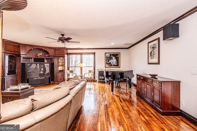 living room featuring crown molding, dark hardwood / wood-style flooring, ceiling fan, and a textured ceiling