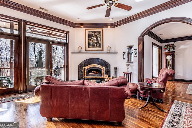 living room with ceiling fan, ornamental molding, wood-type flooring, and a high end fireplace