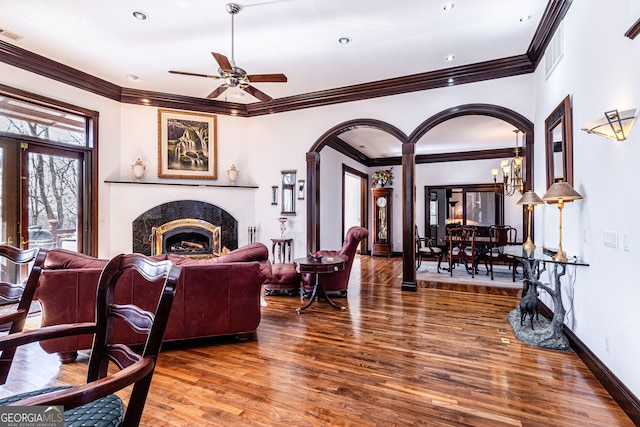 living room with ceiling fan with notable chandelier, dark hardwood / wood-style flooring, a high end fireplace, and ornamental molding