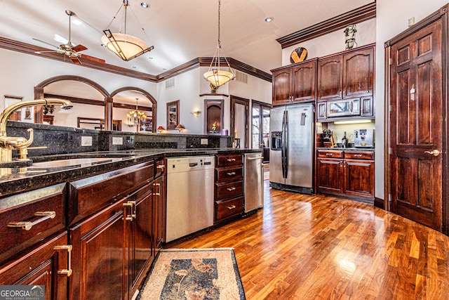 kitchen with dark stone countertops, crown molding, appliances with stainless steel finishes, light hardwood / wood-style floors, and ceiling fan