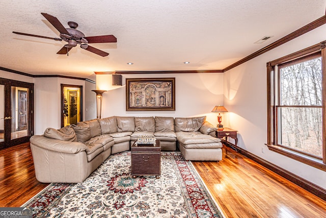 living room with a textured ceiling, crown molding, ceiling fan, and hardwood / wood-style floors