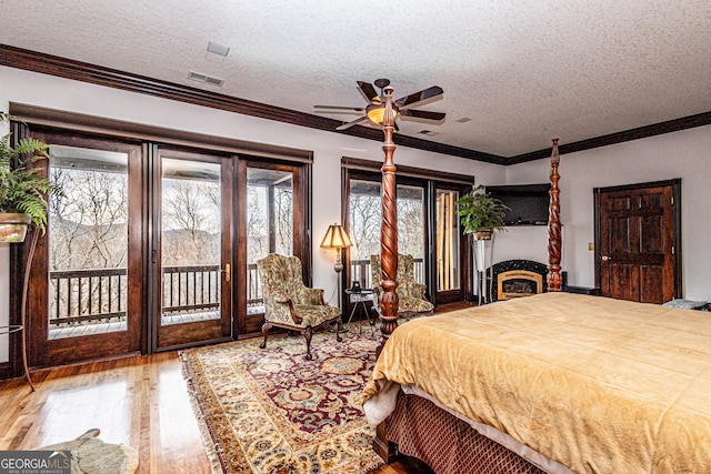 bedroom featuring hardwood / wood-style flooring, a textured ceiling, access to outside, and ceiling fan