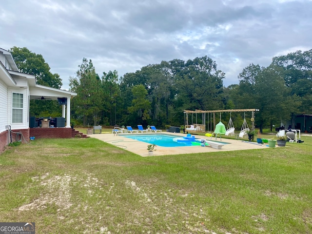 view of swimming pool with ceiling fan, a patio area, and a yard