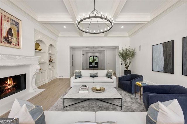 living room with beam ceiling, ornamental molding, an inviting chandelier, and light hardwood / wood-style floors